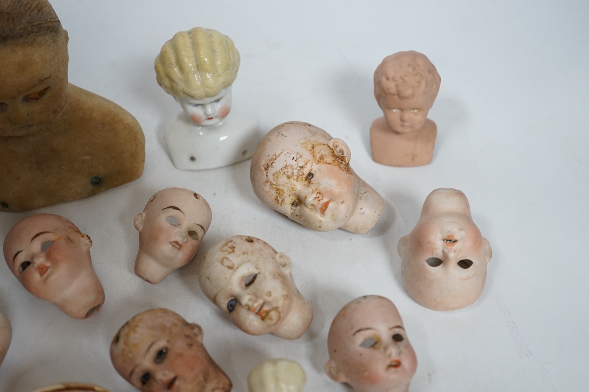 Twelve small bisque doll heads and a wax head